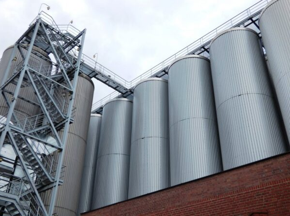 Silver cement storage silos behind red brick wall and stairway